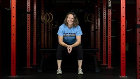 Kara Hume sitting at a workout bench surrounded by workout racks.